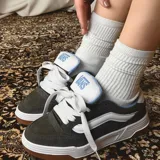 Championes Vans modelo Hylane, de diseño robusto en color marrón oscuro con detalles en blanco y azul. Presentan la icónica banda lateral de la marca en blanco, cordones gruesos, suela de plataforma blanca y base de goma color caramelo.