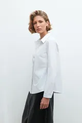 Camisa blanca de manga larga con cuello clásico y cierre frontal con botones.