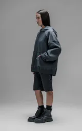 Hoodie oversize de algodón con diseño bicolor en gris oscuro y gris medio. Presenta capucha forrada, mangas raglán con recortes técnicos y un bolsillo frontal tipo canguro con un compartimento adicional con solapa.