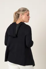 Saco negro suelto con capucha y mangas largas. El interior de la capucha y los puños son de color gris claro.