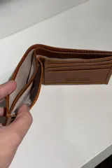 Billetera de cuero con diseño clásico y minimalista, con acabado brillante y logo grabado en la esquina inferior derecha.