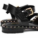Sandalias chatitas color negro de cuero 100% natural, con diseño de tiras cruzadas en el empeine, pulsera al tobillo con hebilla metálica dorada y apliques de tachas doradas alrededor de las tiras y la suela.