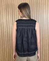 Musculosa de lino color blanco, de corte holgado, con cuello en V, detalles de tablas y frunces en los hombros, y dobladillo desflecado.