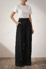 Pantalón de lino de corte amplio y tiro alto, con pretina estructurada, tablas frontales y detalle de mini bolsillo lateral con tapa y botón.