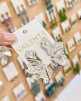 Caravanas de diseño orgánico con forma de flor, acabado metálico brillante en color plateado.