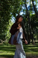 Bolso tipo tote de gran tamaño, confeccionado en una combinación de cuero marrón y gamuza celeste. Presenta un diseño de franjas verticales, con asas resistentes y un bolsillo interior para mayor funcionalidad.