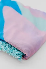 Pareo de playa blanco con estampado de hojas verdes y borde de encaje con flecos.