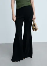 Pantalon de vestir negro de corte flare con diseño de campana, tejido fluido, bolsillos laterales y cierre oculto.