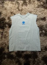 Musculosa sin mangas color gris melange, con cuello redondo y corte amplio. Presenta un estampado central de un sol estilizado en color azul con la palabra "Hermod" debajo.