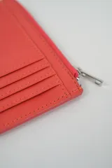 Billetera pequeña color negro con cierre de cremallera plateado y apliques de tachas metálicas redondas en la parte frontal.