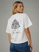 Remera blanca con silueta boxy, manga corta y cuello redondo. Presenta un estampado de línea negra en la espalda que ilustra la parte trasera de una cabeza con cabello corto recogido y la inscripción "Whatever".