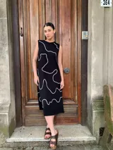 Vestido midi negro con estampado de líneas blancas, sin mangas y cuello redondo.
