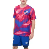Remera de fútbol Umbro del Club Nacional de Football modelo Press, con diseño estampado abstracto en tonos rojo y azul, cuello redondo y mangas cortas. Cuenta con el logo de Umbro y el escudo del club bordados en el pecho.