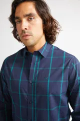 Camisa de manga larga con cuello clásico y cierre frontal abotonado. Presenta un estampado de cuadros en tonos azul marino y rojo. Confeccionada en algodón, cuenta con un corte slim fit y logo bordado en el pecho.