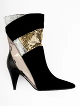Bota corta de caña media color negro con paneles de cuero sintético texturizado y detalles metalizados en dorado y plateado. Tiene taco fino y punta en pico.
