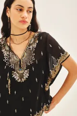 Blusa de gasa negra con escote en V, mangas amplias de largo irregular y bordados detallados con canutillos, lentejuelas y mostacillas. Incluye viso al tono con breteles regulables.