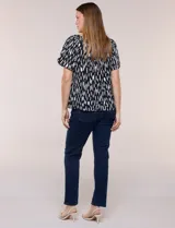 Blusa de poliéster azul con estampado botánico y floral, de silueta holgada y fluido diseño. Cuenta con escote redondo elastizado con frunces y mangas cortas amplias.