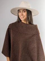 Poncho de tejido texturizado en color marrón chocolate, con cuello amplio y diseño asimétrico.