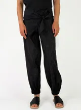 Pantalón negro de corte holgado con diseño a rayas finas, cintura fruncida con lazo ajustable y puños elásticos en los tobillos.