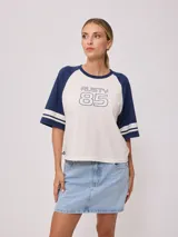 Remera bicolor Rusty con cuerpo verde lima y mangas ranglán grises con dos rayas blancas en los puños. Estampado frontal con el logo de la marca y el número 85.