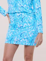 Skort corto con short interno integrado, confeccionado en tejido elastizado de secado rápido con protección solar UPF 50+, estampado abstracto en tonos celestes y blancos, y cintura ancha elastizada.