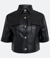 Camisa de manga corta confeccionada en cuero sintético color tostado, con cuello camisero, cierre frontal con botones en forma de corazón y dos bolsillos con solapa en el pecho.