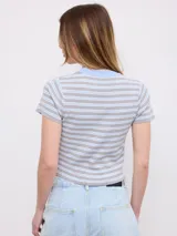 Remera crop de tejido estriado con diseño de rayas horizontales en celeste, marrón y blanco, de manga corta y cuello redondo en color marrón.
