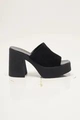 Zapato de plataforma tipo sueco, de empeine amplio en ante, con plataforma alta y taco ancho. Puntera cuadrada y diseño abierto en el talón.