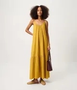 Vestido largo mostaza de viscolino con escote en U, breteles finos y corte evasé con caída fluida. Cuenta con un recorte fruncido en el ruedo.