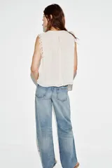 Blusa sin mangas de cuello redondo, con canesú superior de crochet y cuerpo plisado. Cuenta con forro interior y cierre trasero con botón.