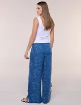 Pantalón palazzo de rayón color azul con estampado paisley blanco, corte amplio, tiro medio-alto con pretina elastizada y aberturas laterales en el puño regulables con lazos.