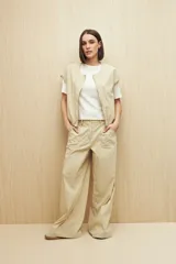 Pantalón ancho (wide leg) de tiro alto, color beige claro, con bolsillos delanteros amplios.