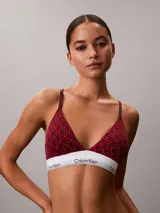 Bralette Calvin Klein de corte triangular, confeccionado en mezcla de algodón elástico y modal, con estampado gráfico en tonos rojos y banda elástica inferior en color blanco con el nombre de la marca en contraste.