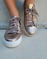 Zapatillas plateadas de cuero con cordones grises y suela blanca.