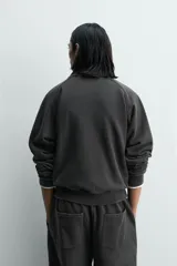 Sudadera de algodón con interior en rizo afelpado, cuello subido, manga larga y cierre frontal de cremallera. Presenta un efecto lavado que le da una apariencia única y bolsillos frontales ocultos en las costuras.