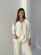 Sweater de punto con cuello en V y mangas largas, de diseño holgado. Presenta un estampado abstracto con pinceladas en color dorado sobre una base blanca.