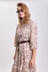 Vestido largo de corte holgado con diseño de paneles escalonados, estampado floral en tonos marrón y beige, cuello redondo y mangas tres cuartos abullonadas.