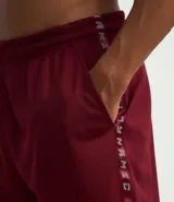 Bermuda deportiva para hombre, color bordó, con tecnología Dry que facilita la evaporación del sudor. Presenta cintura elástica con cordón interno, bolsillos y estampa lateral con lettering.