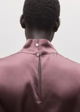 Blusa de seda color rosado oscuro, con cuello alto y diseño recto.