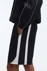 Short deportivo negro con bandas laterales blancas, cintura elástica con cordón ajustable blanco y bolsillos laterales.