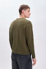 Sweater de punto color verde oliva, con cuello redondo y mangas largas. Diseño clásico con terminaciones acanaladas en cuello, puños y ruedo.