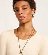 Suéter de punto acanalado color beige, con cuello redondo y mangas largas. Confeccionado en tejido tricot con textura suave y ajuste al cuerpo.