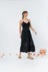 Vestido largo negro con top tejido en crochet y falda de gasa liviana con caída natural. Escote halter con breteles que atan al cuello y detalle de puntilla en la unión del busto.