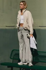 Pantalón deportivo de tejido jaspeado gris, corte ancho y tiro alto con cordón ajustable. Presenta un dobladillo curvo en la parte inferior que realza la silueta.