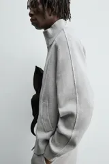 Chaqueta de punto compacto con mezcla de algodón, corte relajado, cuello subido, manga larga, bolsillos laterales de vivo y cierre frontal con cremallera.