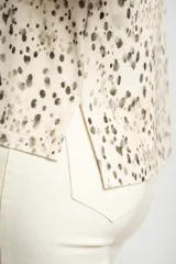 Remera color crema con estampado de manchas marrones, de corte oversize, con cuello en V y mangas cortas.