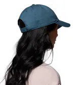 Gorro unisex de algodón color azul verdoso, con visera curva y cierre de velcro ajustable en la parte trasera. Presenta un parche frontal bordado con el logo de Columbia Sportswear y un oso.