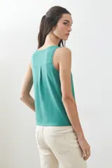 Musculosa verde con escote redondo a la base y sisas anchas.