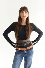 Cinto de cuero marrón con detalle de tachas metálicas circulares en tonos plateados y dorados, con hebilla metálica clásica.