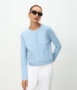 Cardigan de punto celeste de la marca Cortelle, con cuello redondo, mangas largas, cierre frontal de botones y dos bolsillos delanteros aplicados. Presenta detalles de rib en puños y dobladillo.